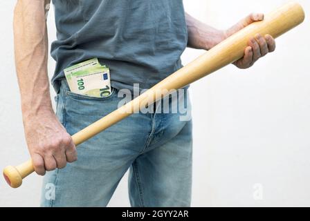 Uomo con banconote in euro in tasca, tenendo una mazza da baseball nelle sue mani - minaccioso. Foto Stock