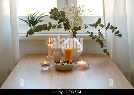 Quattro diverse candele dorate, vaso con rami di eucalipto e una ciotola con biscotti, decorazione festiva per l'Avvento e Natale su un legno Foto Stock