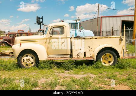 Camion dei pompieri d'epoca della metà del XX secolo, parcheggiato in una discarica con altri vecchi veicoli e uno sfondo blu. ttesque volunteer fire department Foto Stock