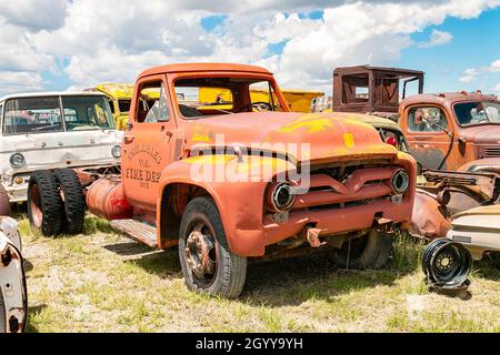 Camion dei vigili del fuoco d'epoca dei vigili del fuoco della Yukon Valley in un cimitero di veicoli rustici sotto un cielo blu brillante Foto Stock