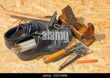 Vari attrezzi e scarpe da lavoro per carpentieri Foto Stock