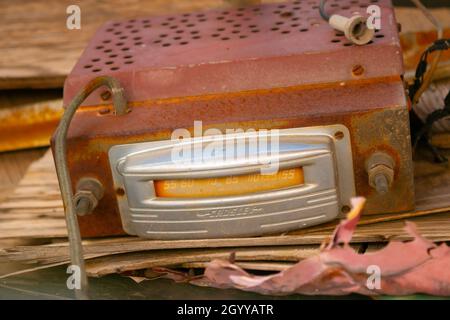 Primo piano di un'autoradio Crosley d'epoca con vernice ruggine e peeling, che mostra dettagli cromati e di frequenza usurati in un ambiente esterno Foto Stock