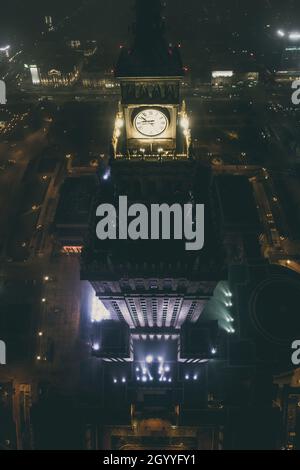 Notevole e alto edificio Palazzo della Cultura e della Scienza coperto di nebbia, illuminato da luci colorate, panorama aereo notturno della città Foto Stock