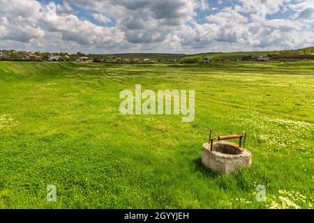 Vecchio pozzo di rivestimento, punto di presa di acqua sul prato. Iurievca, Gagauzja, Repubblica di Moldavia. Foto Stock