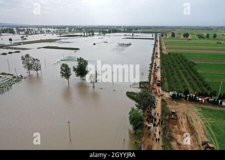 (211010) -- HEJIN, 10 ottobre 2021 (Xinhua) -- Fotografia aerea mostra i soccorritori che fortificano la diga temporanea contro l'alluvione al villaggio di Lianbo a Hejin City, provincia di Shanxi della Cina settentrionale, 10 ottobre 2021. Più di 120,000 persone sono state evacuate temporaneamente dopo continue deflussi innescati alluvioni nella provincia di Shanxi nella Cina settentrionale, ha detto le autorità Domenica. Le inondazioni hanno sconvolto la vita di 1.76 milioni di residenti provenienti da 76 contee, città e distretti, secondo il dipartimento provinciale di gestione delle emergenze. Circa 190,000 ettari di colture sono stati danneggiati e più di 17,000 case c Foto Stock