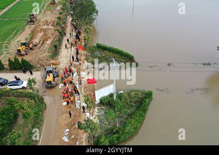 (211010) -- HEJIN, 10 ottobre 2021 (Xinhua) -- Fotografia aerea mostra i soccorritori che fortificano la diga temporanea contro l'alluvione al villaggio di Lianbo a Hejin City, provincia di Shanxi della Cina settentrionale, 10 ottobre 2021. Più di 120,000 persone sono state evacuate temporaneamente dopo continue deflussi innescati alluvioni nella provincia di Shanxi nella Cina settentrionale, ha detto le autorità Domenica. Le inondazioni hanno sconvolto la vita di 1.76 milioni di residenti provenienti da 76 contee, città e distretti, secondo il dipartimento provinciale di gestione delle emergenze. Circa 190,000 ettari di colture sono stati danneggiati e più di 17,000 case c Foto Stock