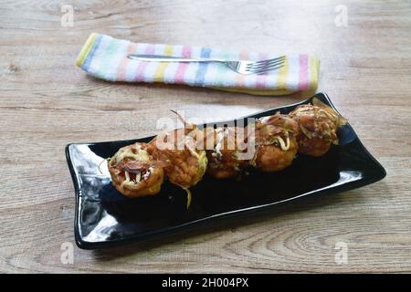 Takoyaki giapponese gnocchi fritti farciti polpo condito maionese condimento pesce secco immersione con salsa di soia dolce sul piatto Foto Stock