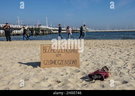 Sopot, Polonia. 10 Ott 2021. I manifestanti di fronte alla bandiera 'sicurezza o umanità' sono visti a Sopot, Polonia il 10 ottobre 2021 persone protestano sotto lo slogan: Non portare i bambini nella foresta. Protestano contro la politica del governo polacco di spingere i rifugiati provenienti dall'Iraq, dall'Afghanistan e da altri paesi della Bielorussia con bambini piccoli nella foresta al confine con la Bielorussia. Il governo polacco nega loro la protezione internazionale e li trasporta illegalmente nella foresta, spingendoli all'estero. Credit: Vadim Pacajev/Alamy Live News Foto Stock