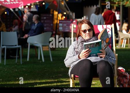 Cheltenham Letteratura Festival, Cheltenham, Regno Unito - Domenica 10 Ottobre 2021 - Un visitatore del Festival gode del sole nel tardo pomeriggio mentre legge bene dal vivo ogni giorno di Alex George - il Festival del libro corre fino a Domenica 17 Ottobre - le vendite del libro sono salite durante la pandemia. Foto Steven Maggio / Alamy Live News Foto Stock