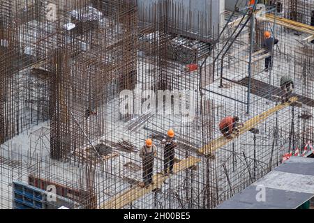 Cantiere con strutture in cemento armato pressofuso. Lavori di cementazione in cantiere. I lavoratori edili versano liquidi Foto Stock