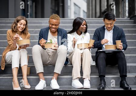 Il team di lavoro parla, mangia e beve sulle scale Foto Stock