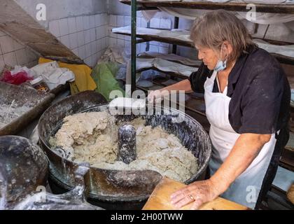 Una donna mescola l'impasto in un tradizionale panificio cipriota villaggio, Arsos villaggio, Cipro. Foto Stock