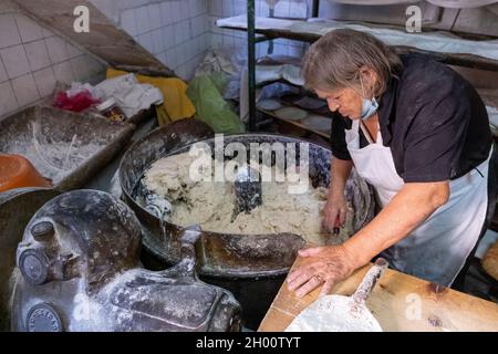 Una donna mescola l'impasto in un tradizionale panificio cipriota villaggio, Arsos villaggio, Cipro. Foto Stock