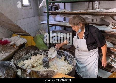 Una donna mescola l'impasto in un tradizionale panificio cipriota villaggio, Arsos villaggio, Cipro. Foto Stock