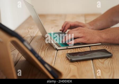 Primo piano delle mani di un uomo che digita su una tastiera, cercando informazioni. Un copywriter freelance sta lavorando ad un progetto. Il concetto di lavoro a distanza. Foto di alta qualità Foto Stock