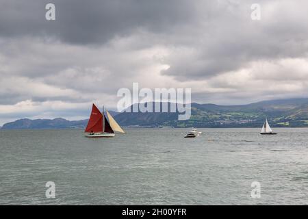 Beaumaris, Galles: Barche a vela sullo stretto di Menai, con montagne di Snowdonia in lontananza. Foto Stock