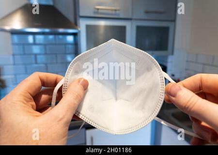 Un uomo che tiene una maschera sul viso in procinto di metterla sopra il viso a casa per Covid-19 Coronavirus, visto dal suo POV (punto di vista). Inghilterra Foto Stock