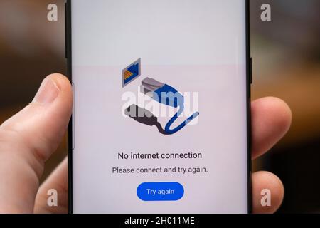 Una mano di un uomo che tiene un telefono con una pagina Web sullo schermo di uno smartphone che dice "Nessuna connessione a Internet" Foto Stock