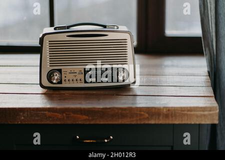 Radio retrò vintage sulla superficie del tavolo in legno vicino alla finestra. Torna agli anni '80. Nostalgia musicale e concetto di vecchia tecnologia. Registratore di antiquariato Foto Stock