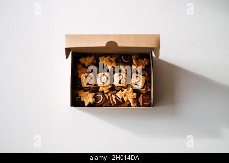 Fai da te biscotti di Natale con 2022 numeri, lettere e forme di albero di Natale in scatola artigianale. Gustosi biscotti di Natale fatti in casa su tavola rustica in legno Foto Stock