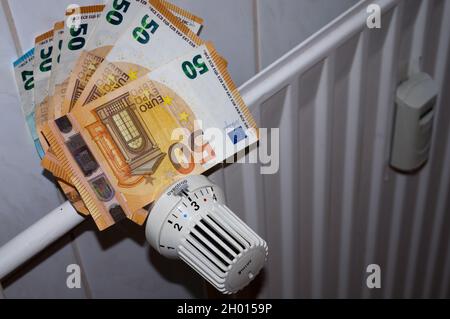 Aumento dei costi di riscaldamento: Radiatori con termostati, misuratore di consumo e banconote Foto Stock