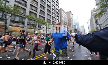 Chicago, Illinois, Stati Uniti. 10 Ott 2021. Un runner afferra una tazza di acqua da una stazione di acqua verso sud su state Street durante la 43rd Bank of America Chicago Marathon, domenica 10 ottobre 2021. Si stima che circa 35,000 persone partecipino ai 26.2 chilometri di percorso pianeggiante che attraversa diversi quartieri dal centro città a molte comunità circostanti a Chicago. (Credit Image: © Pat A. Robinson/ZUMA Press Wire) Foto Stock