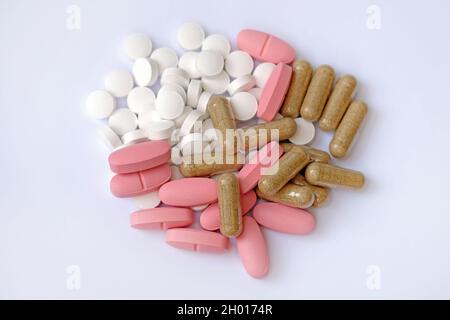 Compresse rotonde bianche, compresse ovali rosa e capsule su sfondo bianco. Integratori alimentari sotto forma di compresse, vista dall'alto. Pillole e capsule si chiudono Foto Stock