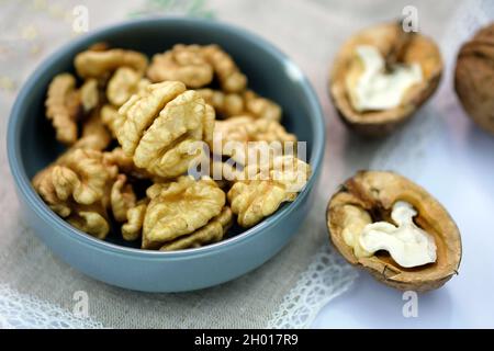 Vista dall'alto chicchi di noce. Noci sbucciate e in guscio su una tovaglia sul tavolo. Noci marroni grandi, intere. Foto Stock