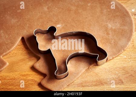 Ritagliare una forma di orso da pasta arrotolata per preparare biscotti di Natale di pan di zenzero fatti in casa Foto Stock