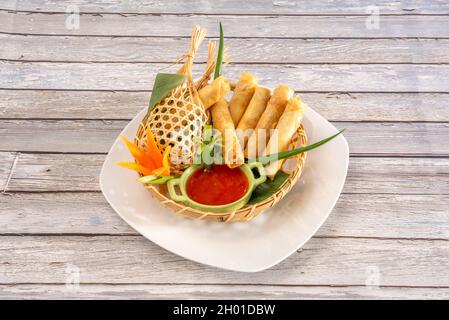 Cestino di vimini con croccanti involtini ripieni di gamberetti cotti con ricette thailandesi e salsa da immersione Foto Stock