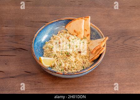 Ciotola in porcellana blu con tovouleh di verdure, zeppa di limone, olio d'oliva e pezzetti di acimo Foto Stock