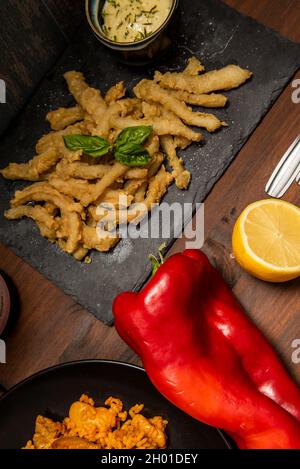 Piatti spagnoli serviti come tapas nel ristorante. Paella, raba di calamari in pastella e fritta in olio d'oliva con pepe rosso e limone Foto Stock