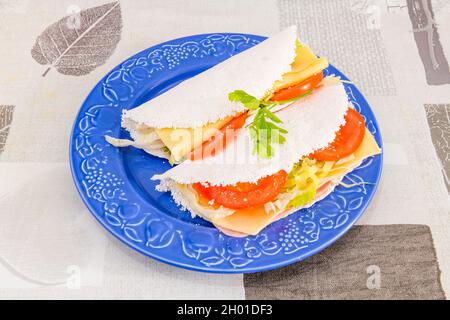 Panino brasiliano con pomodoro, lattuga, prosciutto cotto e fette di formaggio avvolte in una frittata di tapioca Foto Stock