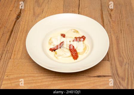 Ricetta per ravioli ripieni di manzo brasato con formaggio cremoso e pomodori secchi su un piatto bianco Foto Stock