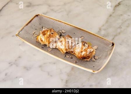 Ravioli ripieni di carne con olio d'oliva con fette di tartufo bianco su un tavolo di marmo bianco Foto Stock