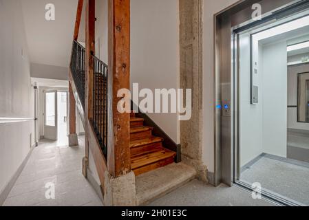 Vecchio edificio ristrutturato con travi in legno e pietra e scale e moderno ascensore Foto Stock