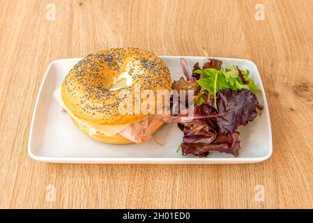 Bagel con crema di formaggio e burro, formaggio fresco e prosciutto cotto con lattuga di quercia Foto Stock