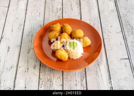 bocconcini di pesce ricoperti di prezzemolo e riso bianco cotto su un piatto d'arancia Foto Stock