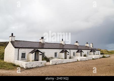 Vecchi cottage pilota sull'isola di Llanddwyn che una volta erano usati per i piloti per guidare le barche lungo lo stretto di Menai sulla costa del Galles del Nord, visto nel mese di ottobre Foto Stock