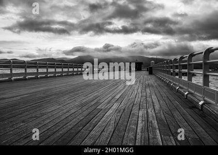 Beaumaris Pier in bianco e nero visto sotto un cielo moody nell'ottobre 2021 sulla costa del Galles del Nord. Foto Stock