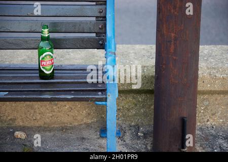 Bottiglia di vetro vuota vista a sinistra su un sedile all'aperto. Foto Stock