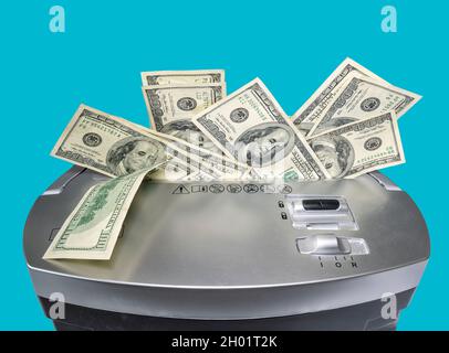 Foto di concetto di una bolletta da 100 dollari che viene sminuzzata da un tritadocumenti raffigurante il valore indebolito del dollaro. Isolato su sfondo blu fisso. Clippin Foto Stock