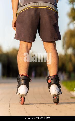 Foto verticale delle gambe di un uomo che pattina con pattini in linea Foto Stock