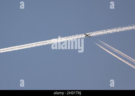 traffico nel cielo. Un aereo che attraversa il sentiero di condensazione che un altro aereo ha segnato nel cielo pochi secondi prima. Mattina presto Foto Stock