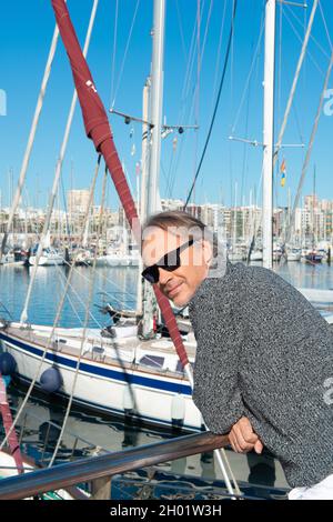 attraente uomo maturo passeggiando lungo il porto turistico in una città Foto Stock