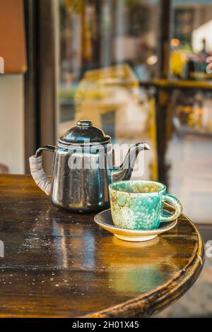 Ancora vita di vecchio Teapot e tazza di tè su tavola di legno. Colazione fuori in città Foto Stock