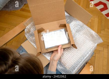 Vista dall'alto di una donna curiosa che sboxe nel soggiorno nuovo pacchetto argento consegna Foto Stock