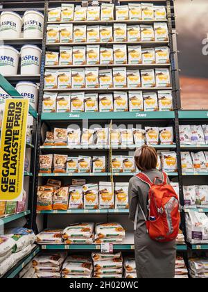 Vista posteriore della donna guardando più tipi di cibo secco cane gatto nel supermercato olandese Foto Stock