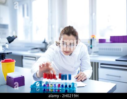 Giovane biologa che lavora con campioni in provette in laboratorio Foto Stock