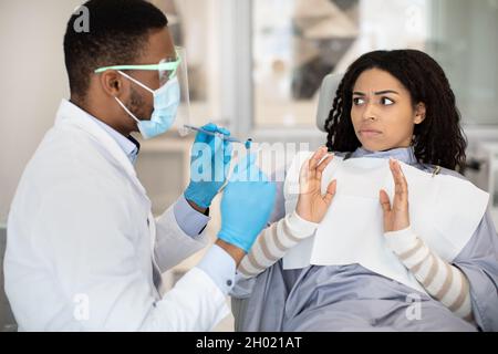 Preoccupata Donna Nera paziente guardando dentista medico con shock durante il check up in Clinic, spaventato African American donna che soffre di trattamento dentale Foto Stock